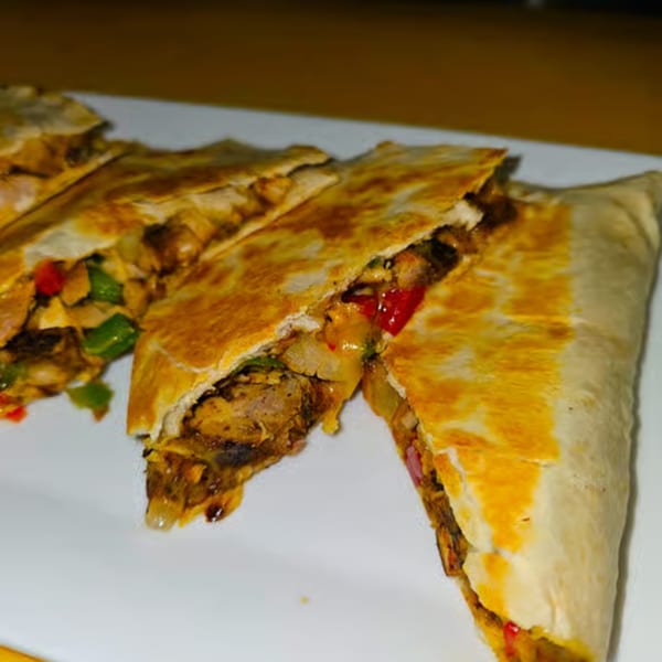 Close-up of Jamaican jerk chicken quesadillas with red and green peppers, onions, and melted cheese.