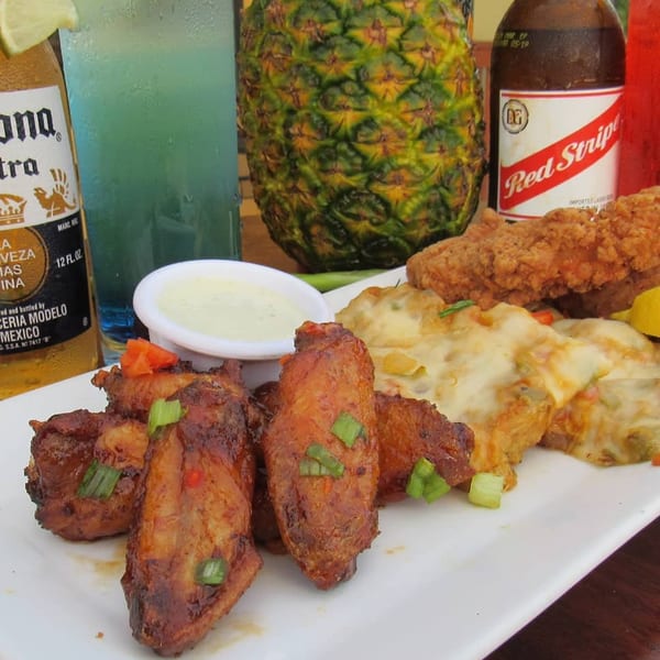 Duckanoo Grill's jerk chicken wings, cheesy potatoes, fried fish, and drinks including Red Stripe.